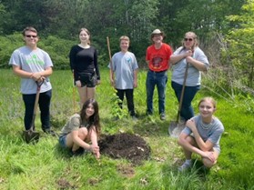 5 youth, Amber and Fred planting a tree