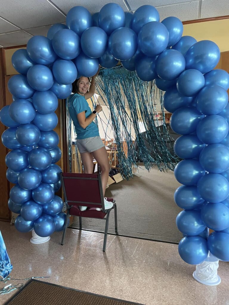 Lauren Lehman under a blue balloon arch.