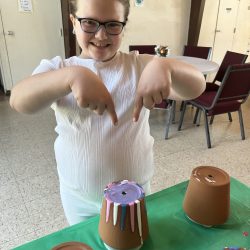 Child pointing to her upside down flower pot with dripped paint on it